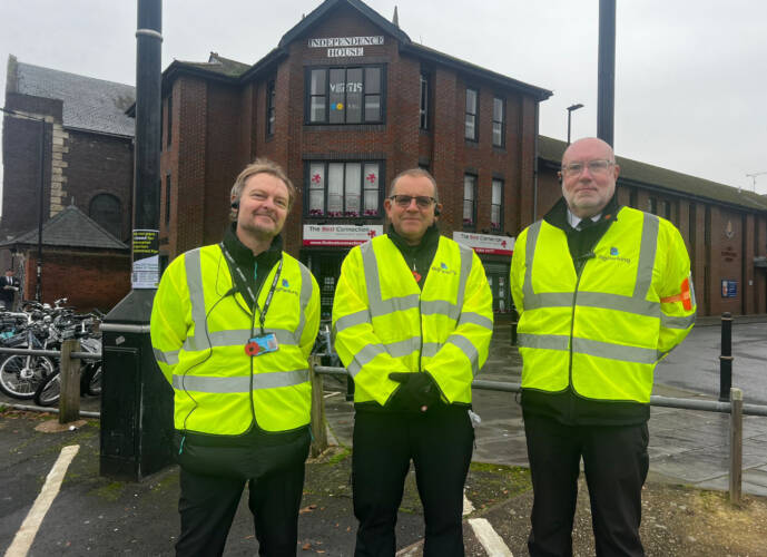Three stweards stood in hi-vis vests