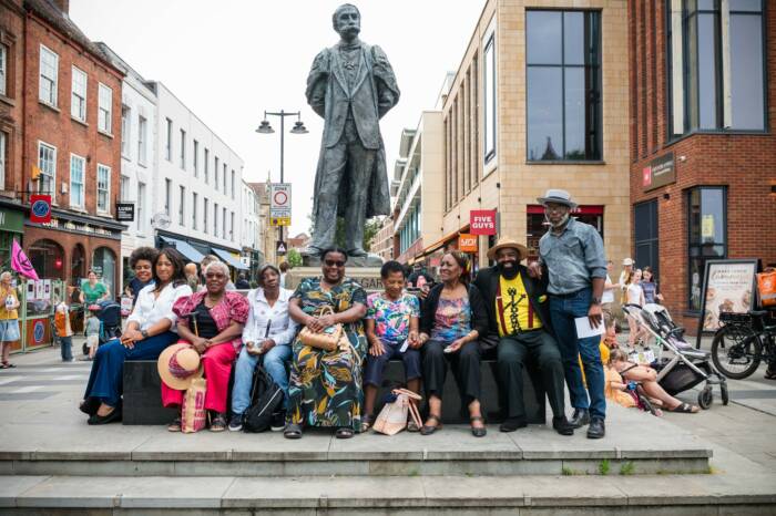 Members of the Afro Caribbean Association sat in front of the Elgar Statue in Worcester City Centre